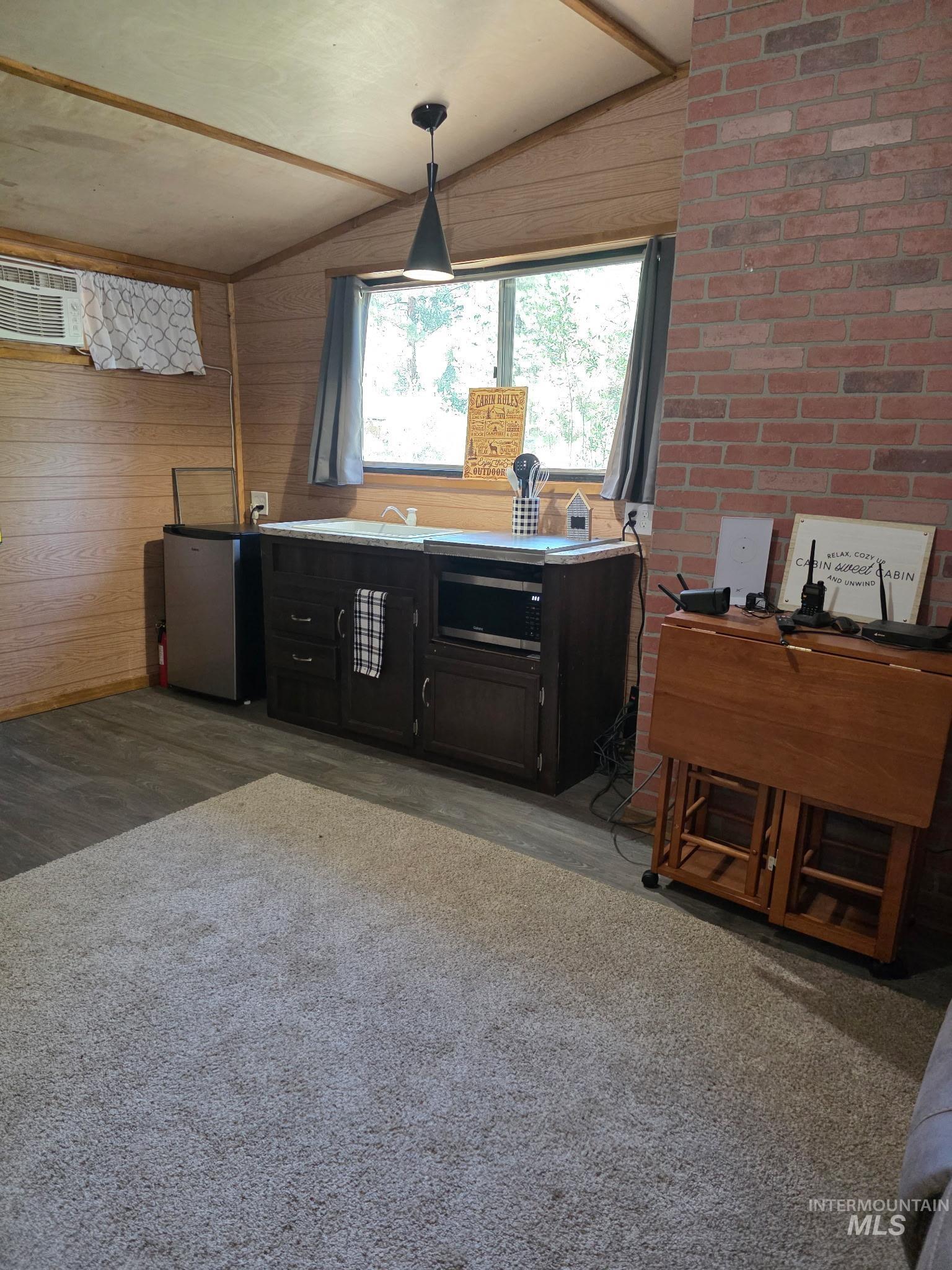 12 Woods Lane Boise, ID 83716 - Photo 8 of 9 Kitchen with freestanding refrigerator, lofted ceiling, dark cabinetry, wood walls, and a wall mounted air conditioner