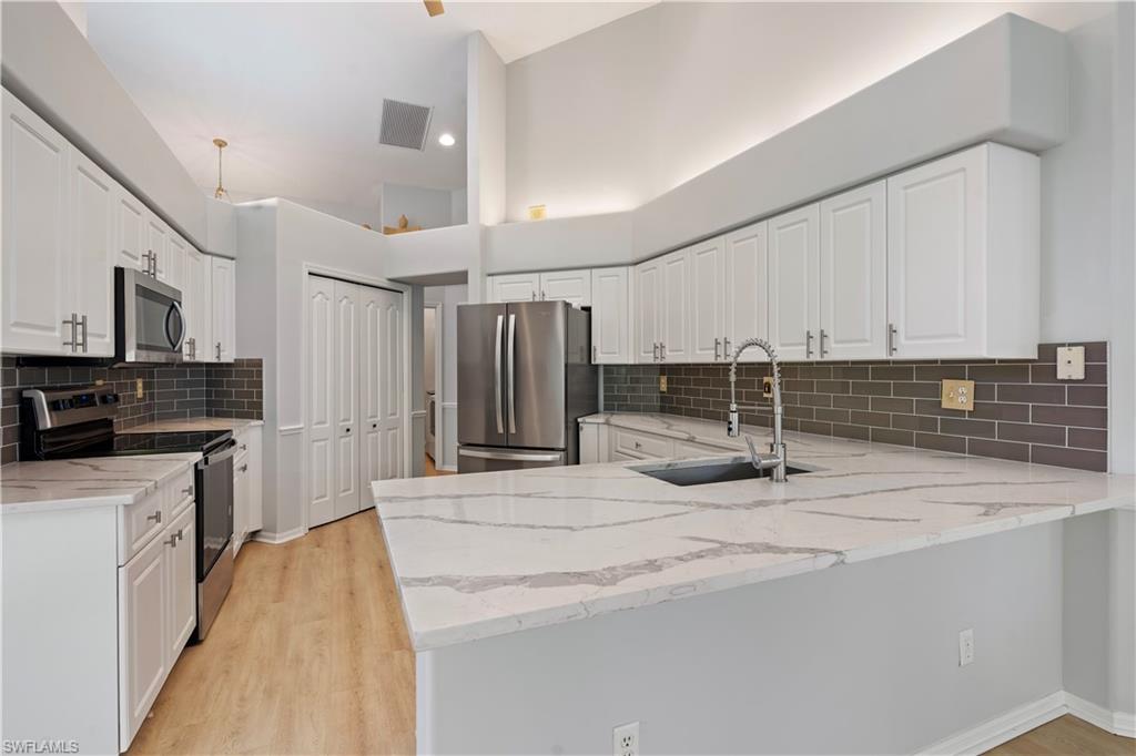 20751 Rivers Ford Estero, FL 33928 - Photo 4 of 36 Kitchen with appliances with stainless steel finishes, light stone counters, and white cabinetry