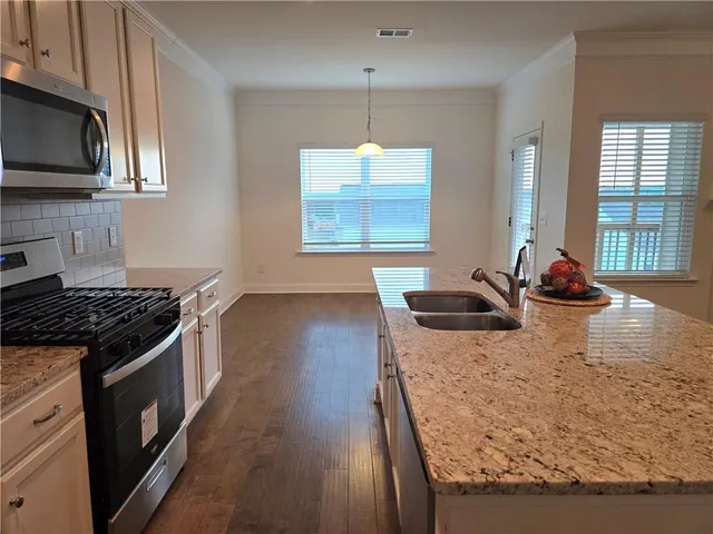 a kitchen with granite countertop a stove a sink and a microwave