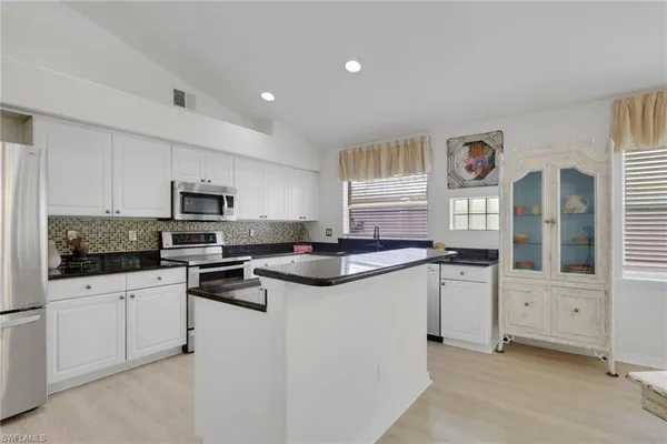 a kitchen with granite countertop white cabinets and white appliances