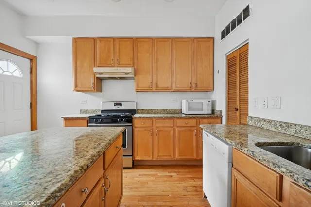 a kitchen with granite countertop wooden cabinets and a stove top oven