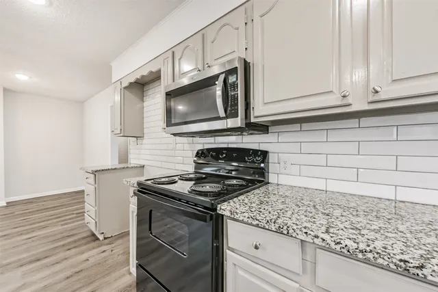 a kitchen with granite countertop cabinets stainless steel appliances and wooden floor