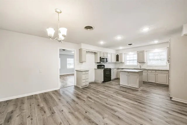 a large white kitchen with wooden floor and stainless steel appliances