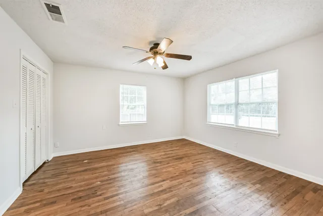 a view of a room with wooden floor and a ceiling fan