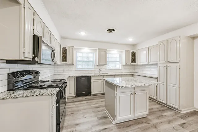 a kitchen with stainless steel appliances granite countertop a stove a sink and a refrigerator