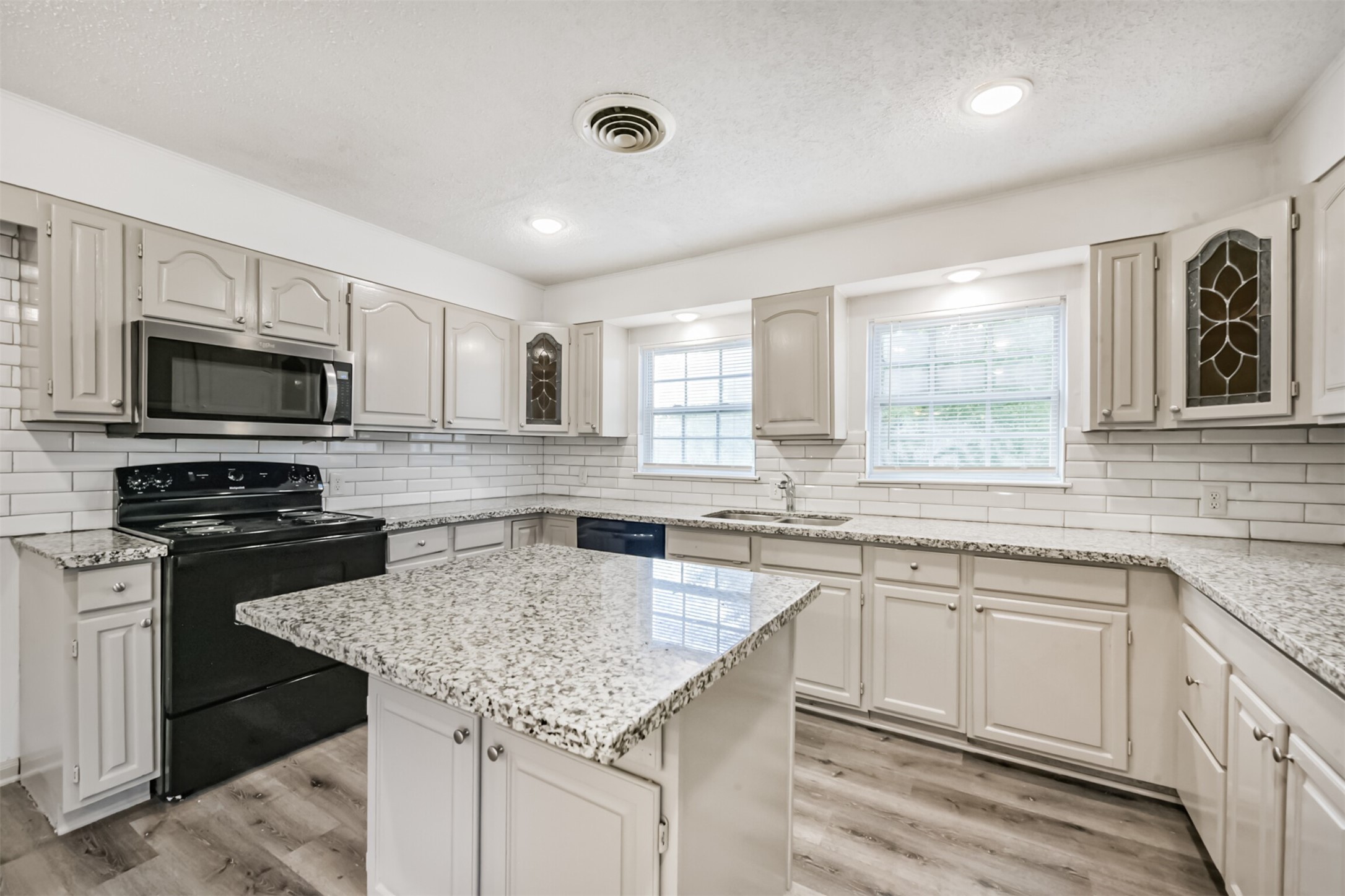 1030 Perkins Drive Bacliff, TX 77518 - Photo 10 of 30 a kitchen with granite countertop stainless steel appliances a sink dishwasher a stove top oven a refrigerator with grey cabinets and wooden floor