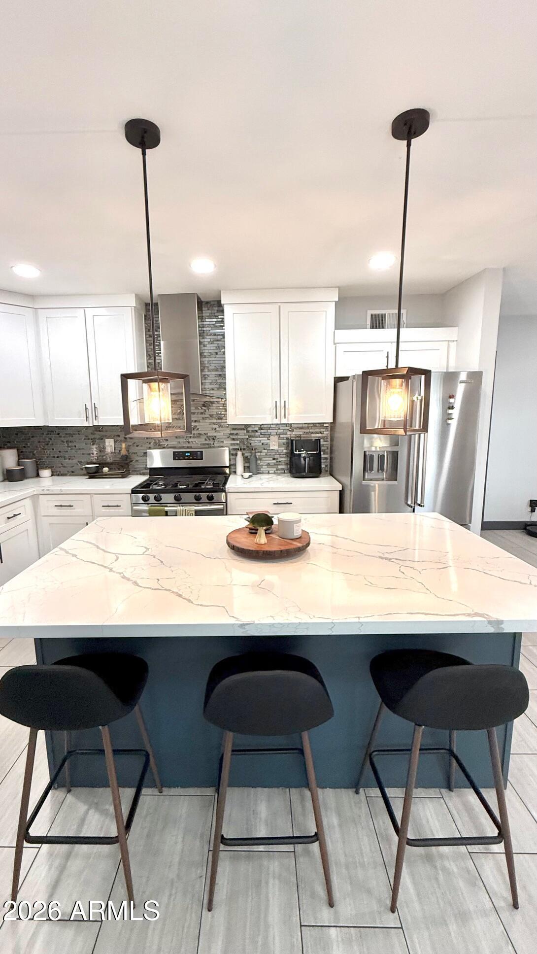 1109 West Indian School Road Phoenix, AZ 85013 - Photo 14 of 38 a kitchen with stainless steel appliances kitchen island granite countertop a table chairs in it and wooden floors