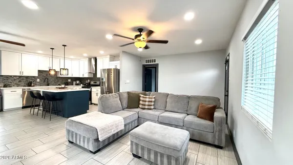 a living room with furniture kitchen view and a large window