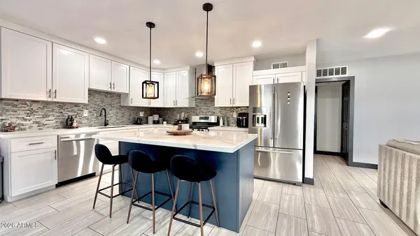 a kitchen with stainless steel appliances granite countertop a sink a stove a refrigerator and island with wooden floor