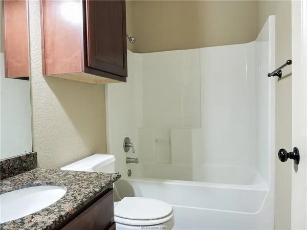 a bathroom with a granite countertop sink toilet and shower