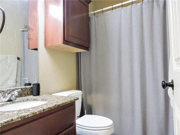 a bathroom with a granite countertop sink toilet and a mirror