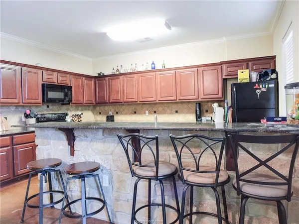 a kitchen with stainless steel appliances granite countertop a table chairs microwave and sink