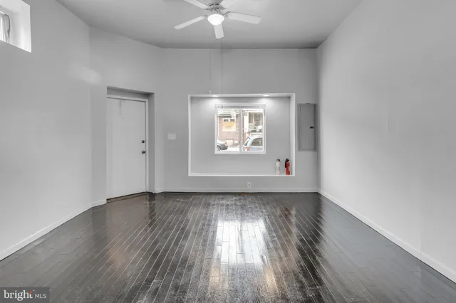 an empty room with wooden floor chandelier fan and windows