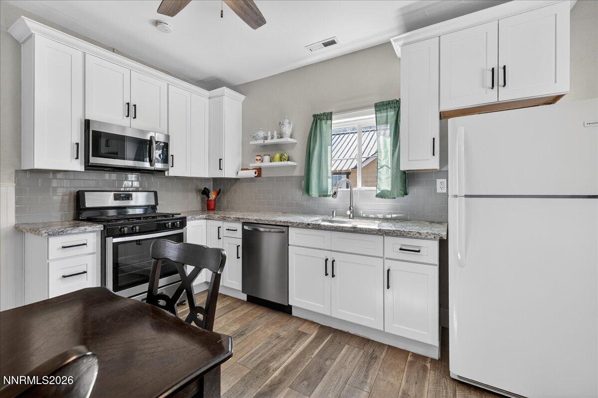 317 South Center Street Yerington, NV 89447 - Photo 10 of 27 a kitchen with stainless steel appliances granite countertop a stove a sink dishwasher a microwave oven and a refrigerator with wooden floor