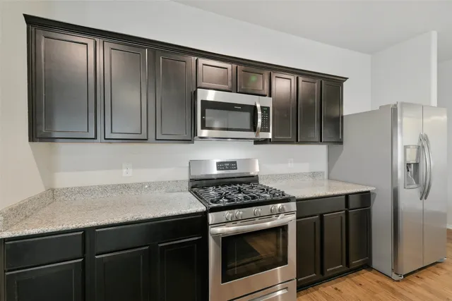 a kitchen with granite countertop stainless steel appliances a stove microwave and refrigerator