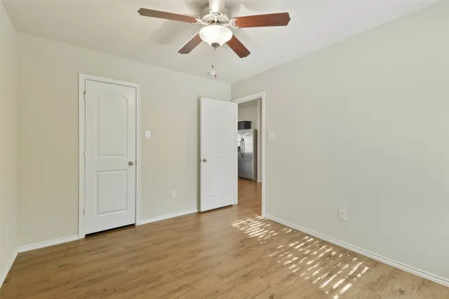 a view of an empty room and chandelier fan