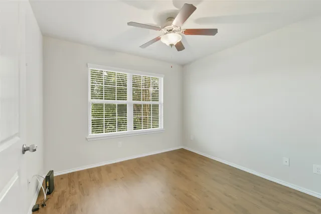 an empty room with a window and a ceiling fan
