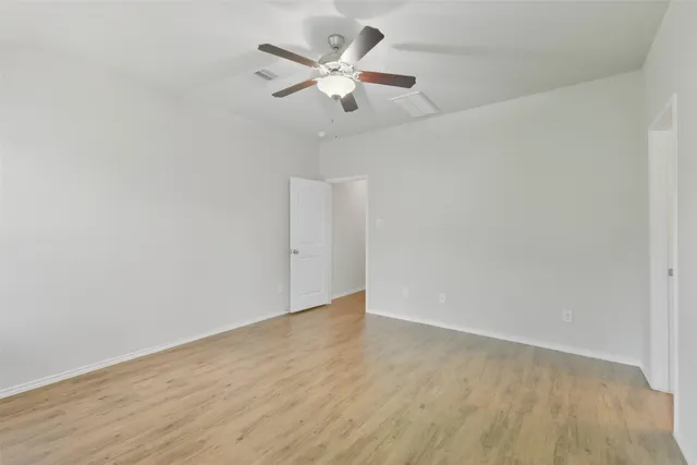 an empty room with wooden floor and ceiling fan