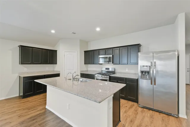 a kitchen with stainless steel appliances granite countertop a sink a microwave a refrigerator and a stove
