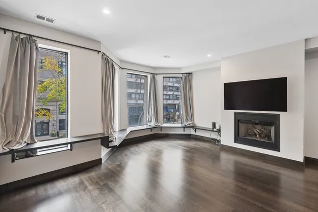 a view of an empty room with window wooden floor and a fireplace