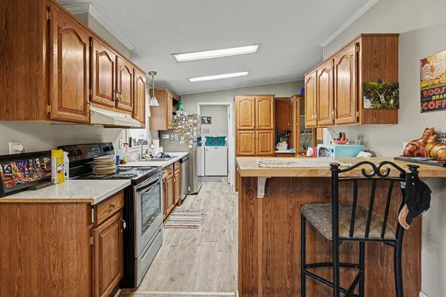 a kitchen with stainless steel appliances granite countertop a stove a sink dishwasher and cabinets with wooden floor