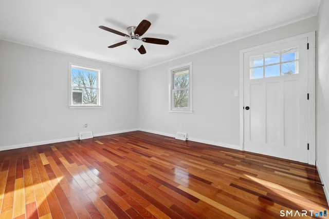 a view of empty room with wooden floor and fan