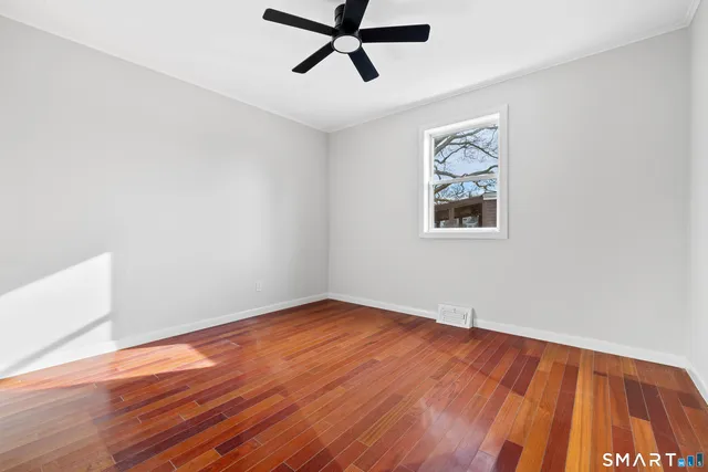 an empty room with wooden floor and ceiling fan