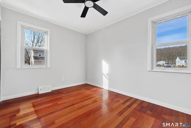 a view of an empty room with wooden floor and a window