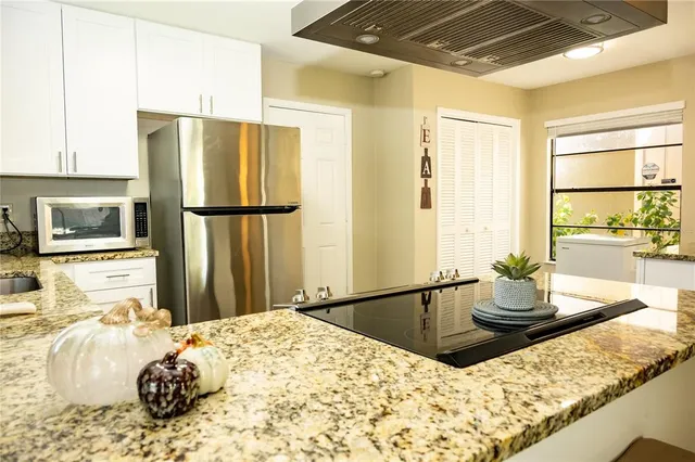 a kitchen with stainless steel appliances a stove a sink and white cabinets with wooden floor next to windows