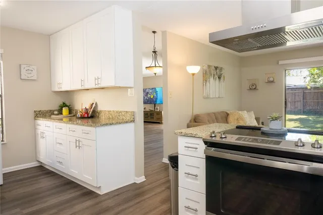 a kitchen with kitchen island stainless steel appliances a dining table chairs sink and cabinets