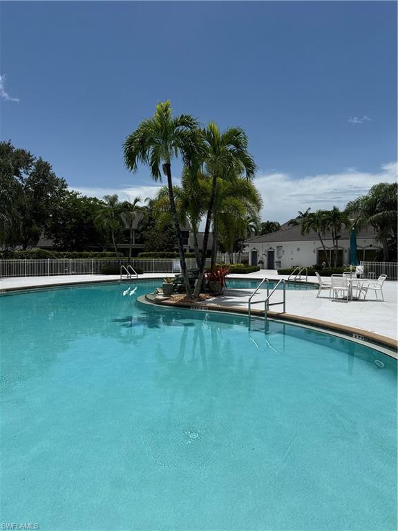 975 Partridge Circle, Unit 202 Naples, FL 34104 - Photo 12 of 16 a view of a swimming pool with a table and chairs