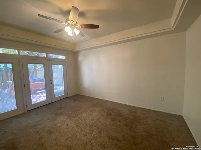 a view of an empty room with chandelier fan and fire place