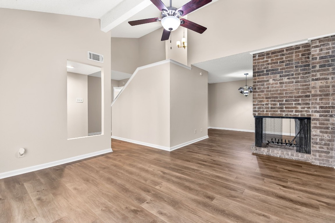 a view of an empty room with wooden floor and a fireplace