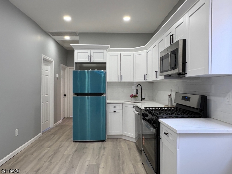 456 Harrison Street, Unit 2 Passaic, NJ 07055 - Photo 7 of 17 a kitchen with a refrigerator a stove top oven and cabinets