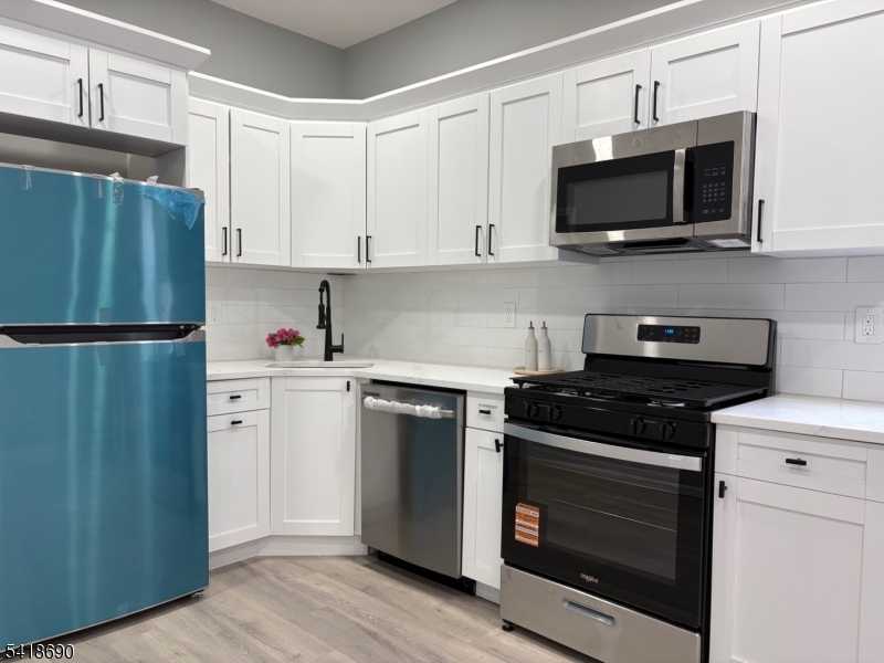 456 Harrison Street, Unit 2 Passaic, NJ 07055 - Photo 8 of 17 a kitchen with cabinets stainless steel appliances and wooden floor