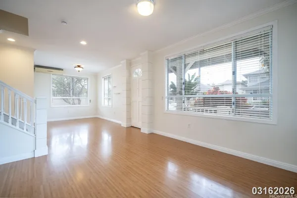 a view of an empty room with wooden floor and a window