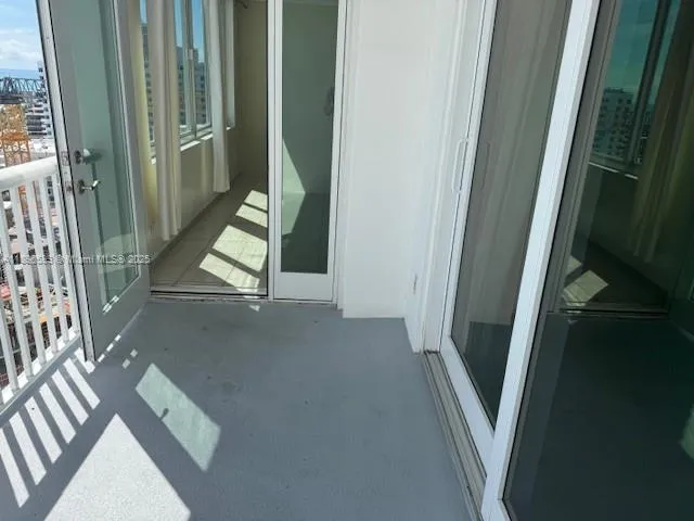 a view of kitchen and empty room with wooden floor