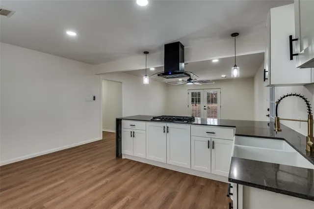 a kitchen with stainless steel appliances a sink a stove a refrigerator and island with wooden floor