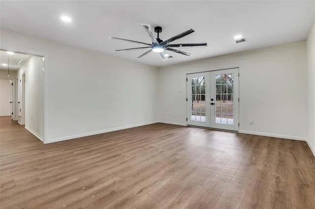 a view of an empty room with window and wooden floor