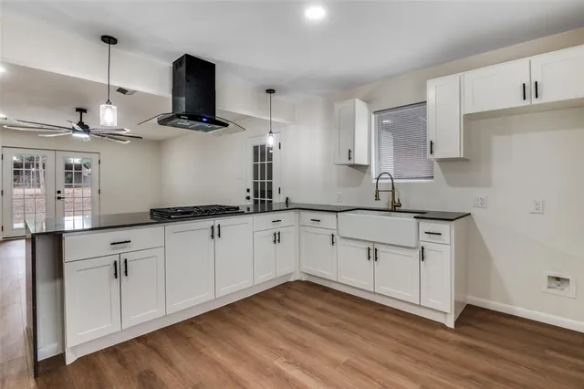 a kitchen with stainless steel appliances granite countertop a sink a stove and wooden floors