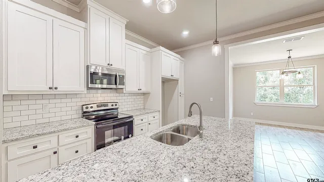 a kitchen with granite countertop a stove sink and cabinets