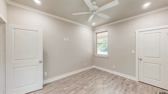 an empty room with wooden floor ceiling fan and windows