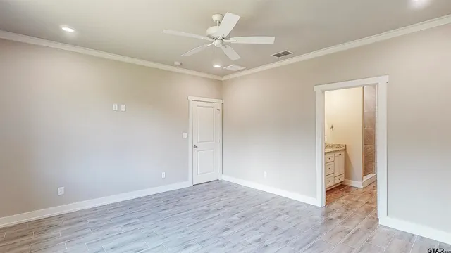 an empty room with wooden floor and a ceiling fan