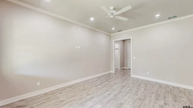 an empty room with wooden floor and ceiling fan