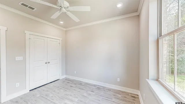 an empty room with wooden floor fan and windows