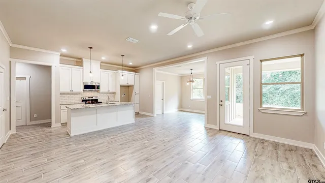 a large kitchen with kitchen island a stove a refrigerator wooden floor and white cabinets