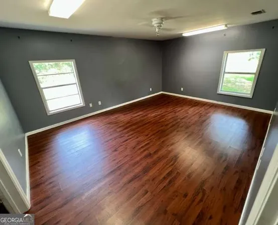 a view of empty room with wooden floor and fan