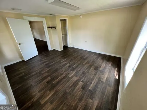a view of an empty room with wooden floor and stairs