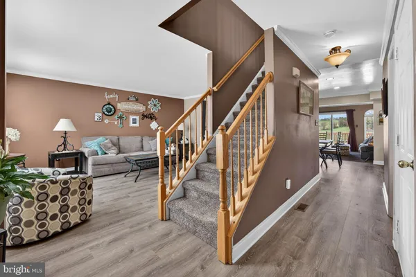 a living room with furniture and stairs with wooden floor