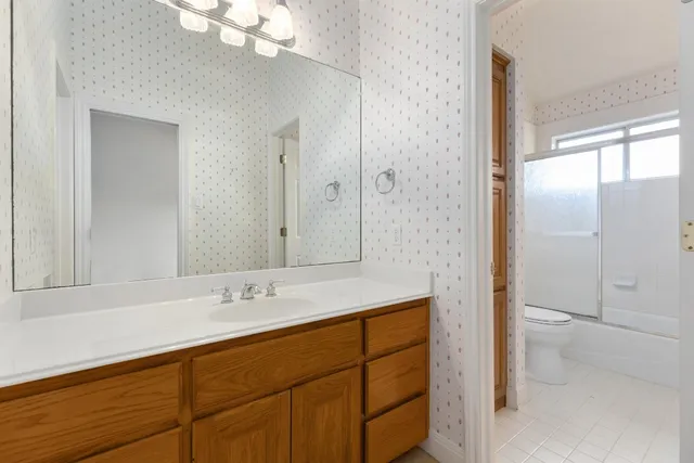 an empty room with windows and chandelier fan